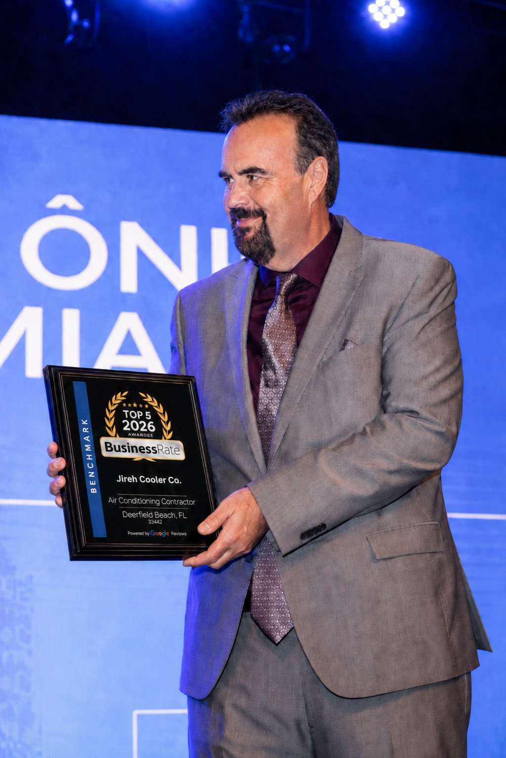 Moyses Oliveira holding Jireh Cooler's BusinessRate Top 5 Award for 2026