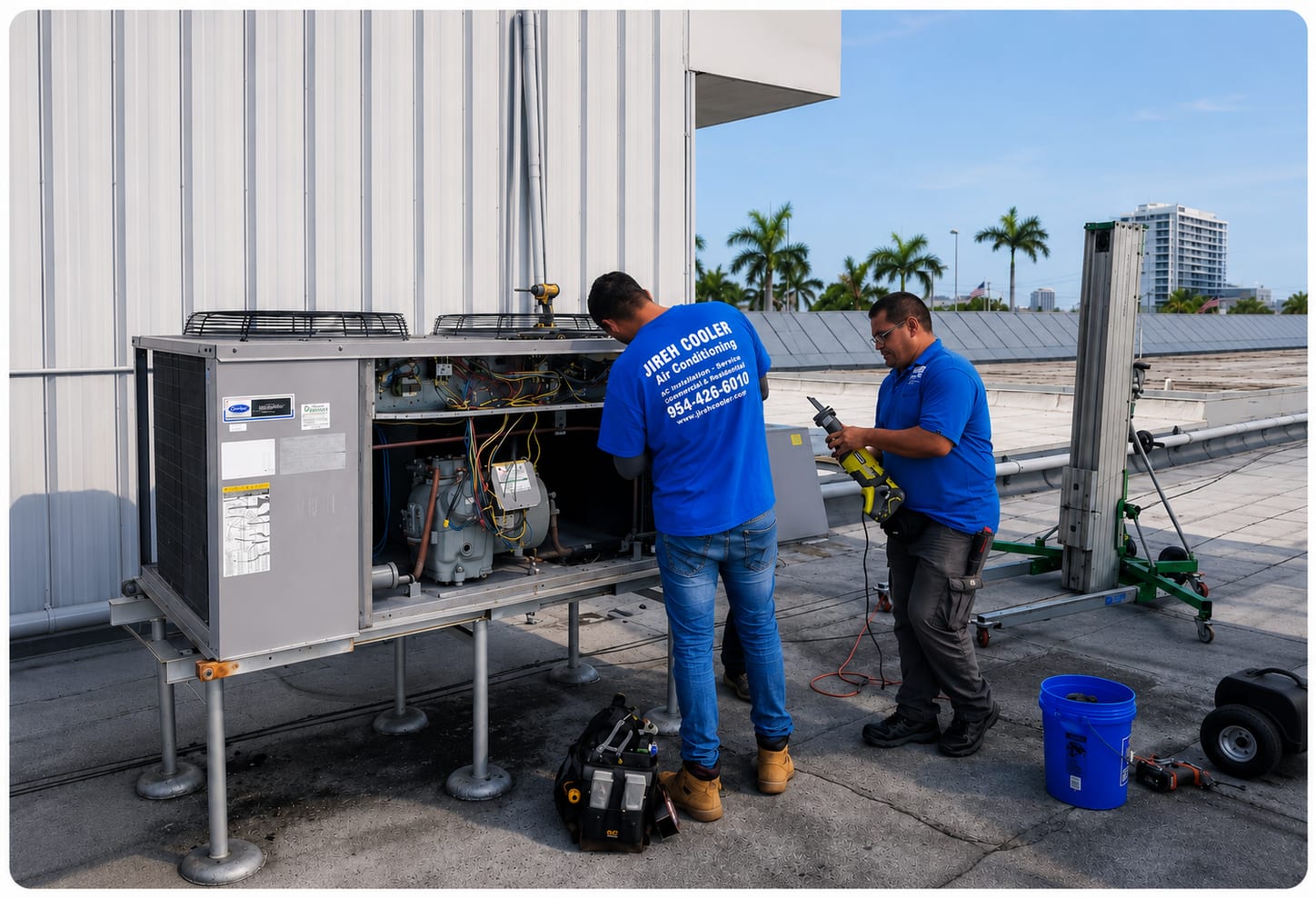 Two Jireh Cooler technicians in blue shirts servicing a commercial rooftop HVAC unit